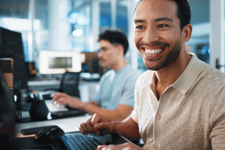 A mixed race man who is smiling whilst working as a gaming developer A mixed race man who is smiling whilst working as a gaming developer
