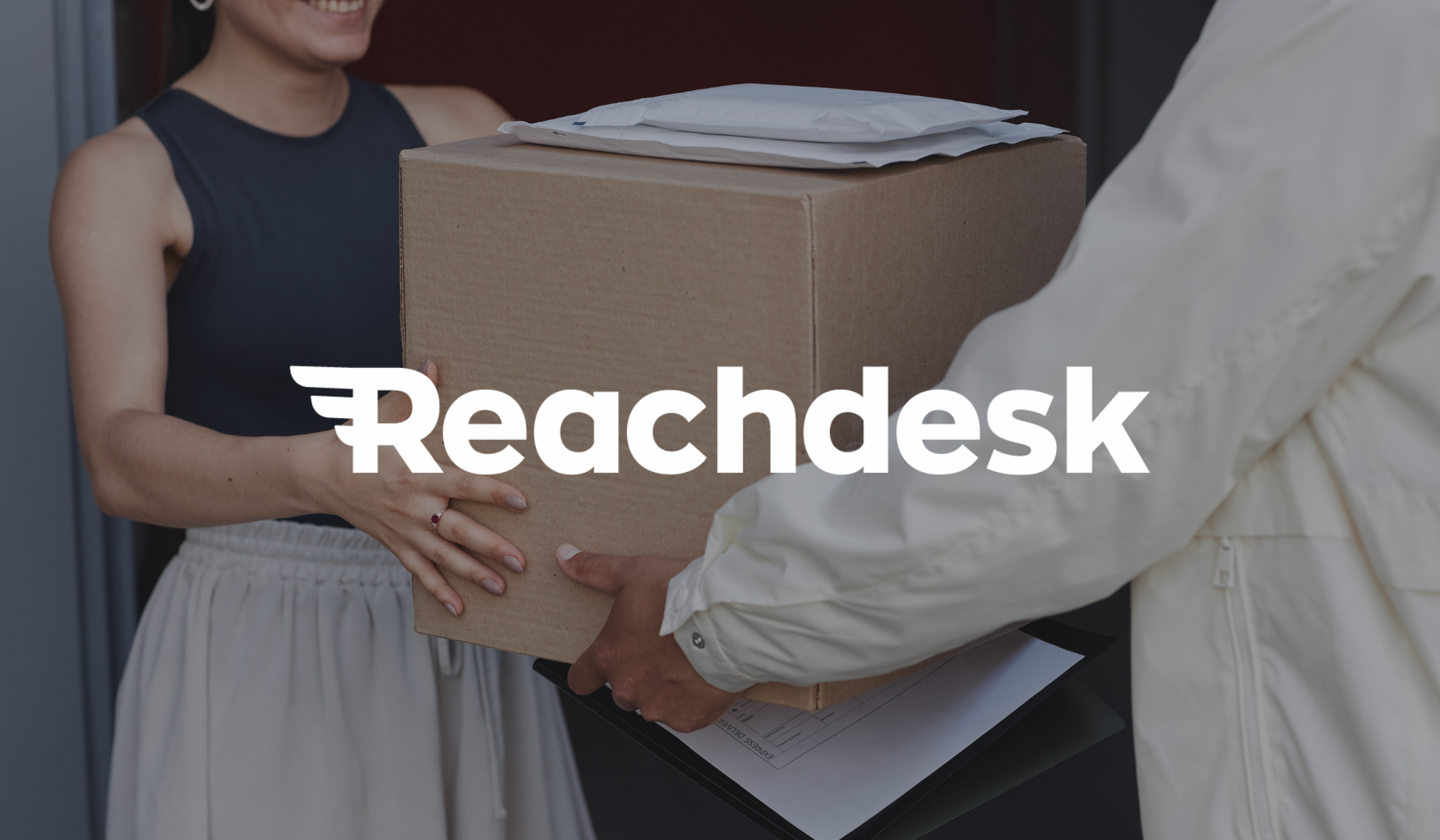 Reachdesk logo overlayed onto a photo of a man providing a cardboard box to another woman
