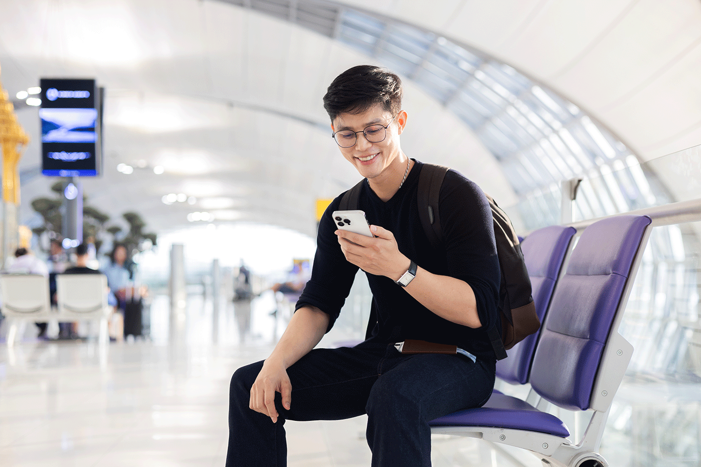 A man sits on his phone smiling 